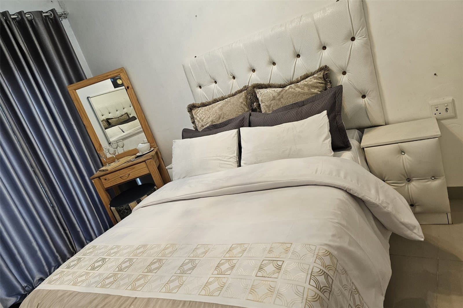 Double bed with white tufted headboard and fresh linen